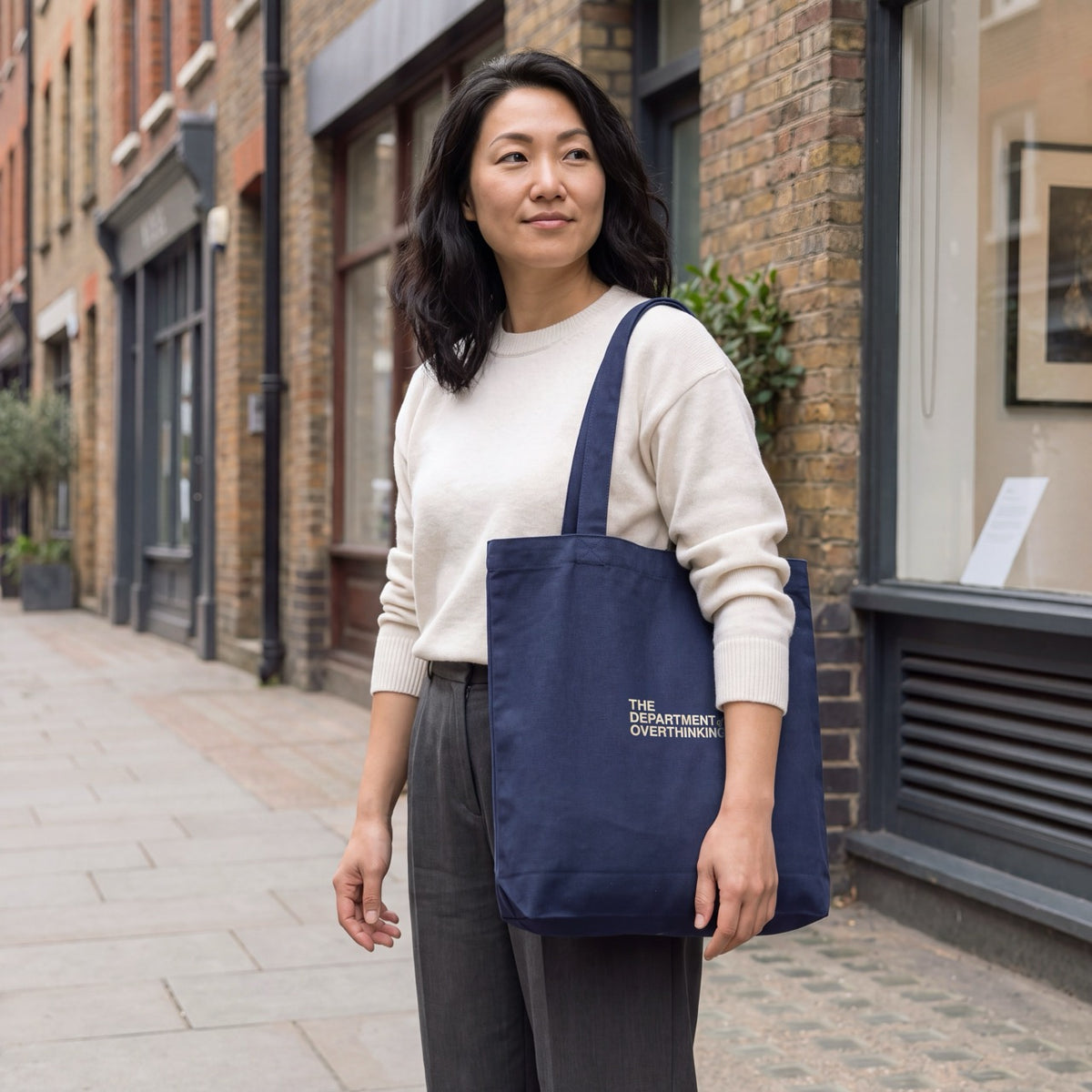 Woman wearing a navy Department of Overthinking embroidered tote bag over her shoulder