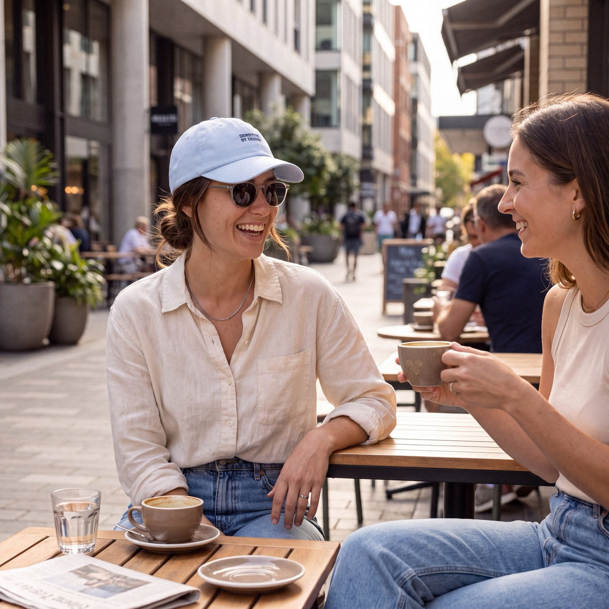 Woman wearing a light blue embroidered cap while sitting at an outdoor café
