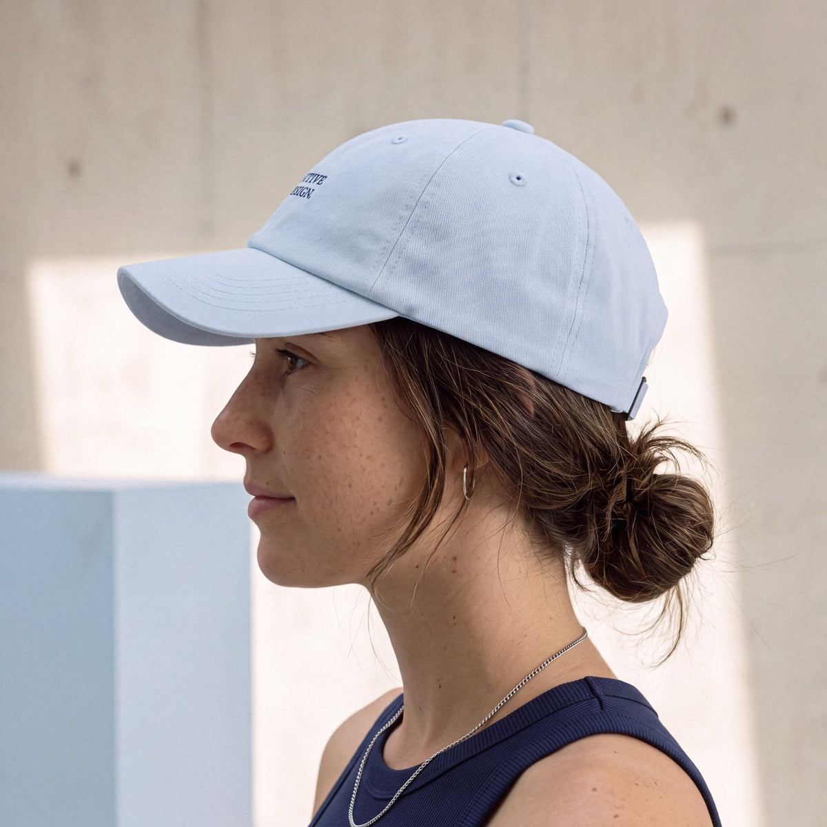 Side profile of woman wearing a light blue Department of Overthinking cap