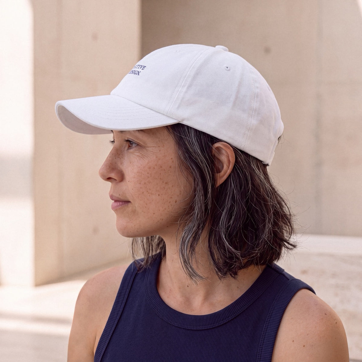 Side profile of woman wearing a white Department of Overthinking cap