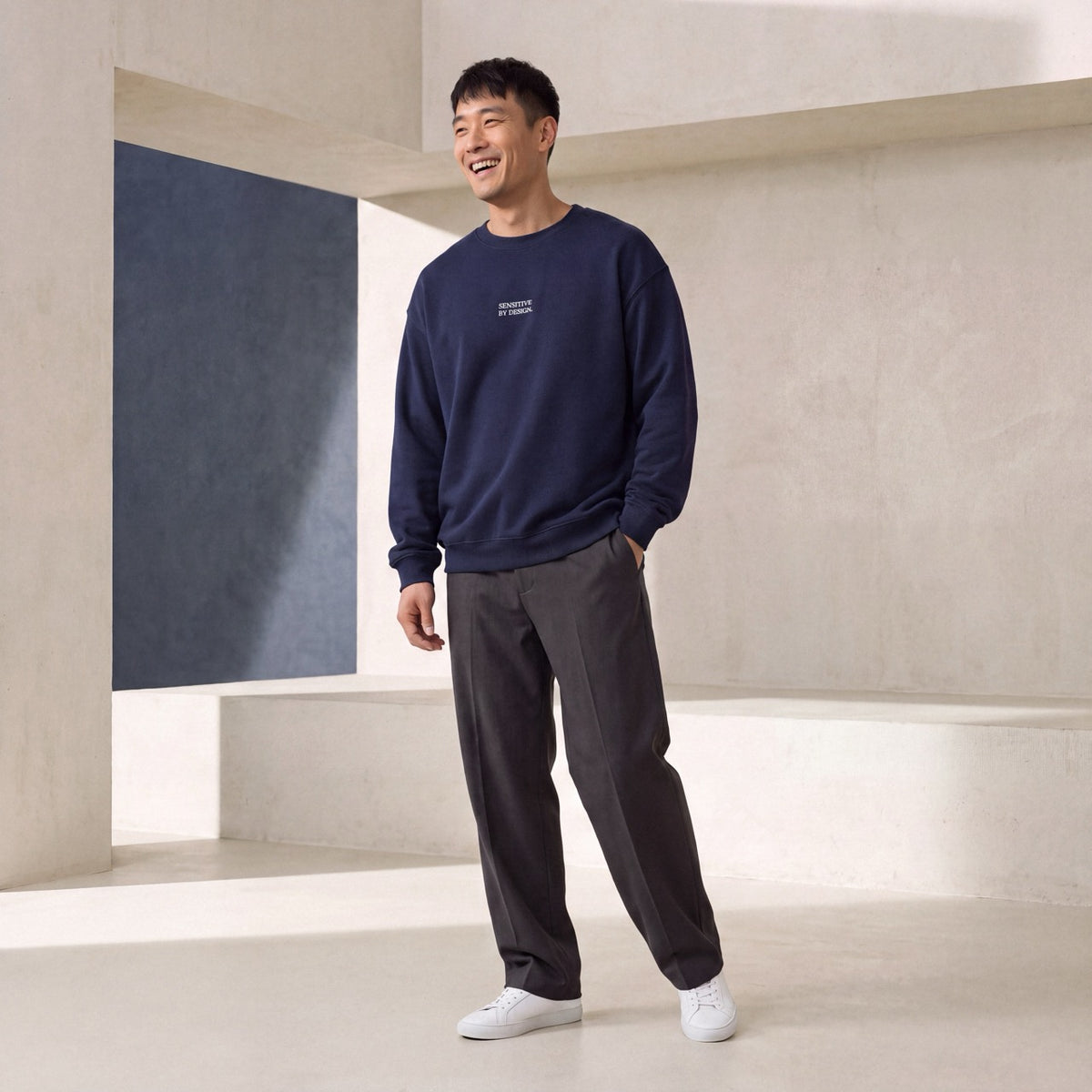 Front view of man wearing a navy SENSITIVE BY DESIGN. sweatshirt