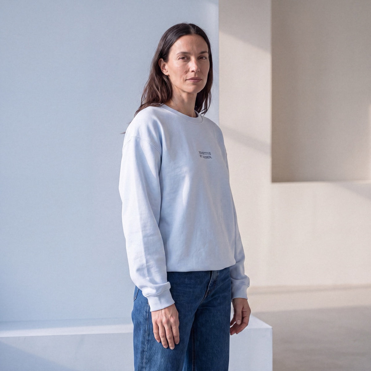 Side view of woman wearing a light blue embroidered crewneck sweatshirt