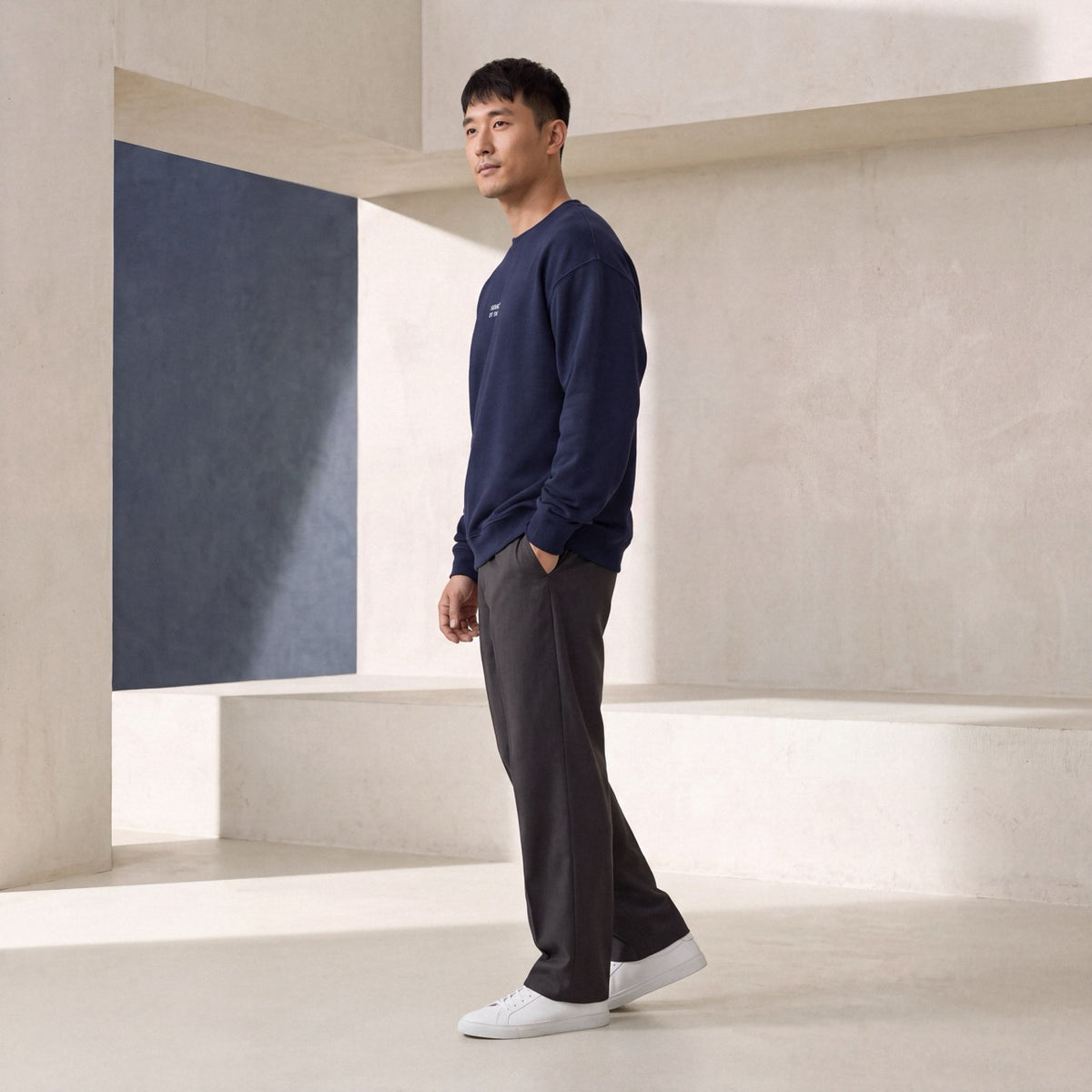 Side view of man wearing a navy embroidered crewneck sweatshirt