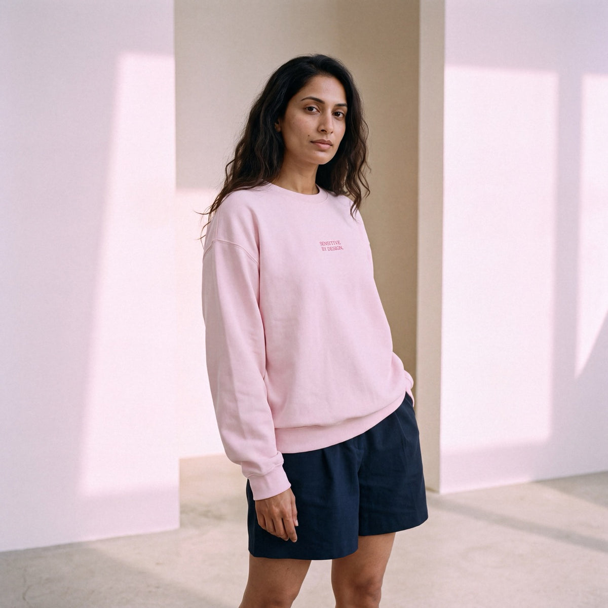Side view of woman wearing a light pink embroidered crewneck sweatshirt